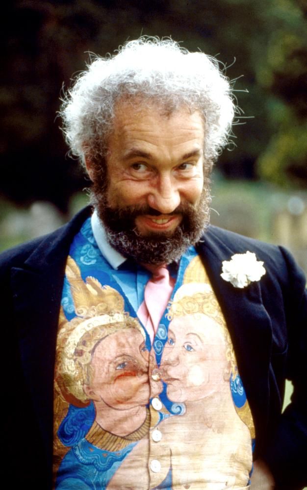 man smiles into camera wearing waistcoat, Simon Callow as Gareth in Four Weddings and a Funeral