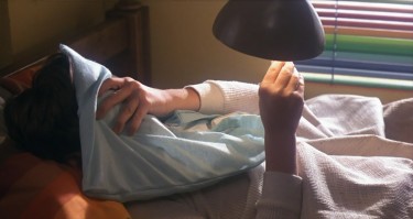 boy covers his face and puts thermometer by lamp; still from E.T.