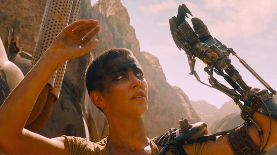 woman with black makeup on her eyes and a prosthetic arm; Charlize Theron as Furiosa in Mad Max: Fury Road