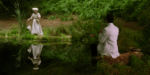 woman in white dress is reflected in water in front of man in white jacket; Helena Bonham-Carter and Daniel Day Lewis in A Room with a View